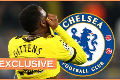 Jamie Gittens pulls his shirt over his face next to Chelsea club crest.