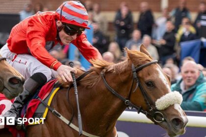 Jockey Rowan Scott dressed in red silks riding Boyne Lady to victory