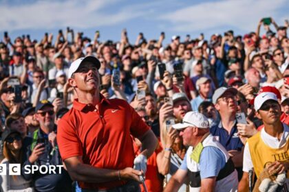 The gallery watches on as Rory McIlroy hits his approach into the 17th