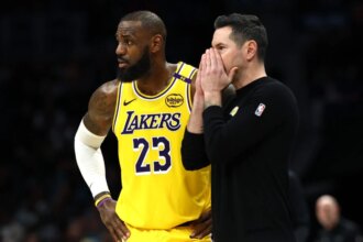 Los Angeles Lakers head coach JJ Redick and #23 LeBron James speak during the first half of the game against the Charlotte Hornets at Spectrum Center.