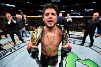 Henry Cejudo poses with his two UFC titles after defeating Marlon Moraes at UFC 238