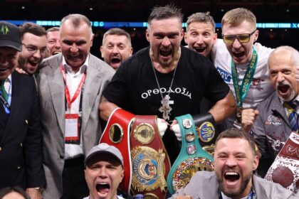 Oleksandr Usyk celebrates with teammates after the match, belt in hand