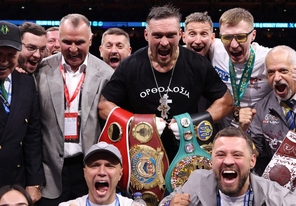 Oleksandr Usyk celebrates with teammates after the match, belt in hand