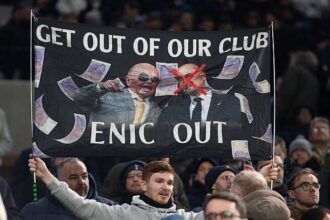 Tottenham fan holds up a banner protesting against the club