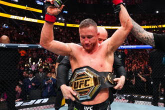 Justin Gaethje raises his hands and wraps them around his UFC title at UFC 324
