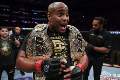 Daniel Cormier celebrating with two UFC title belts after UFC 230