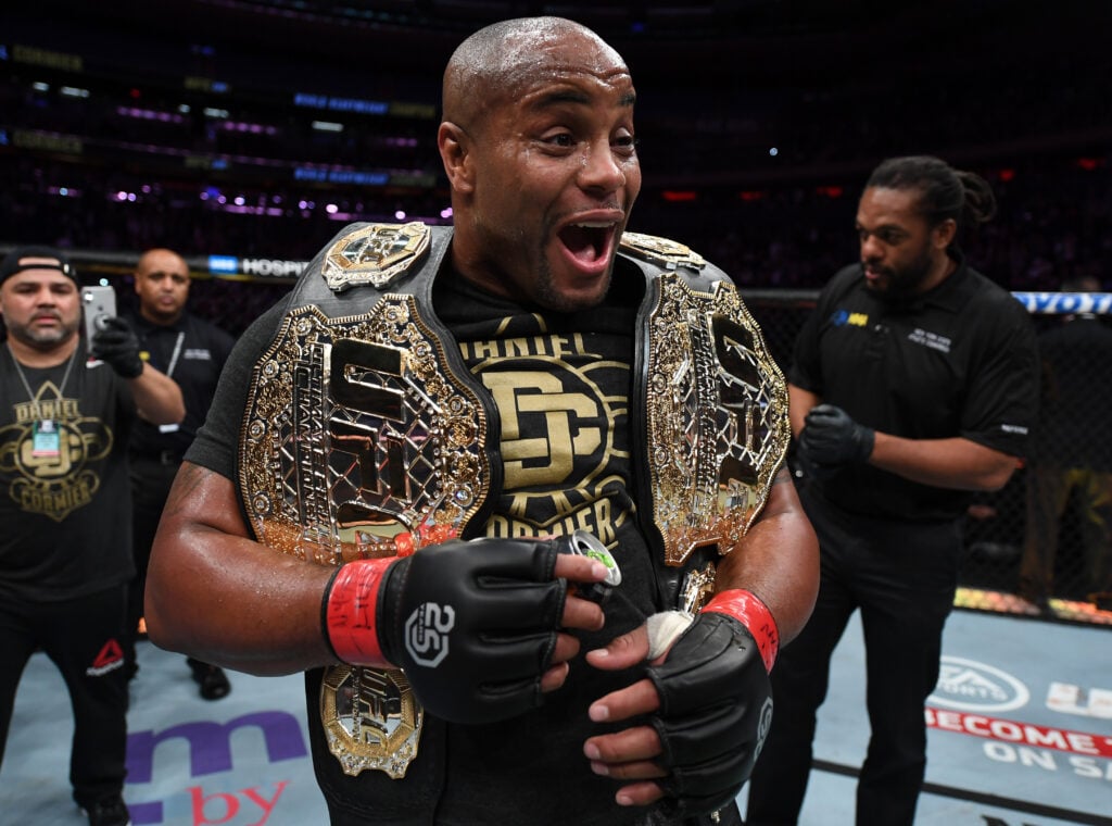 Daniel Cormier celebrating with two UFC title belts after UFC 230