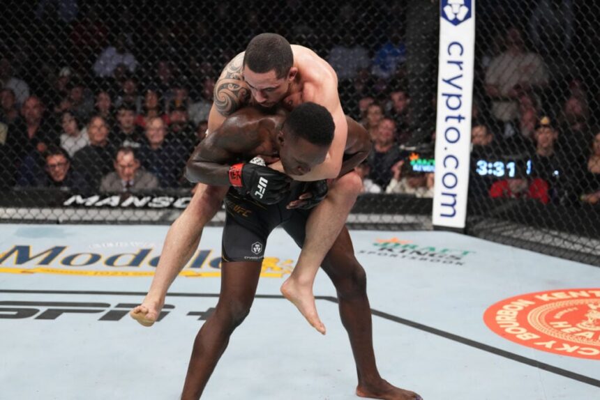 Robert Whittaker rides on Israel Adesanya's back