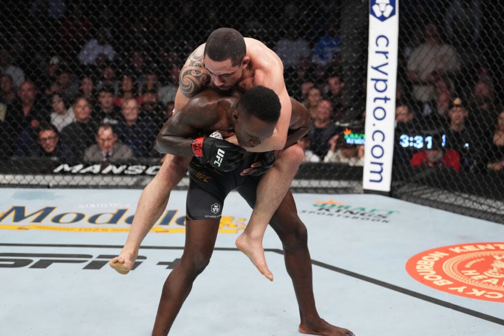 Robert Whittaker rides on Israel Adesanya's back